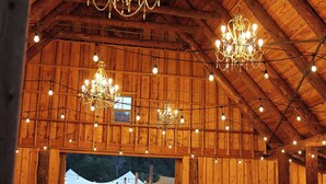 Ein Innenraum mit Holzwänden und hoher Decke, ausgestattet mit Kronleuchtern und Lichterketten.
