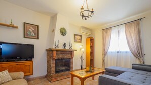 A living room with a television, fireplace, sofa, and a table.