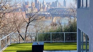 A modern building with a glass balcony overlooking a cityscape and a river.