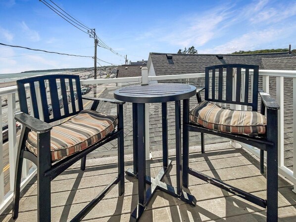 A deck with two chairs and a table, overlooking a beach and a road. - Sweet Serenity (York Beach)
