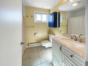 A bathroom with a toilet, sink, and mirror. - Sweet Serenity (York Beach)