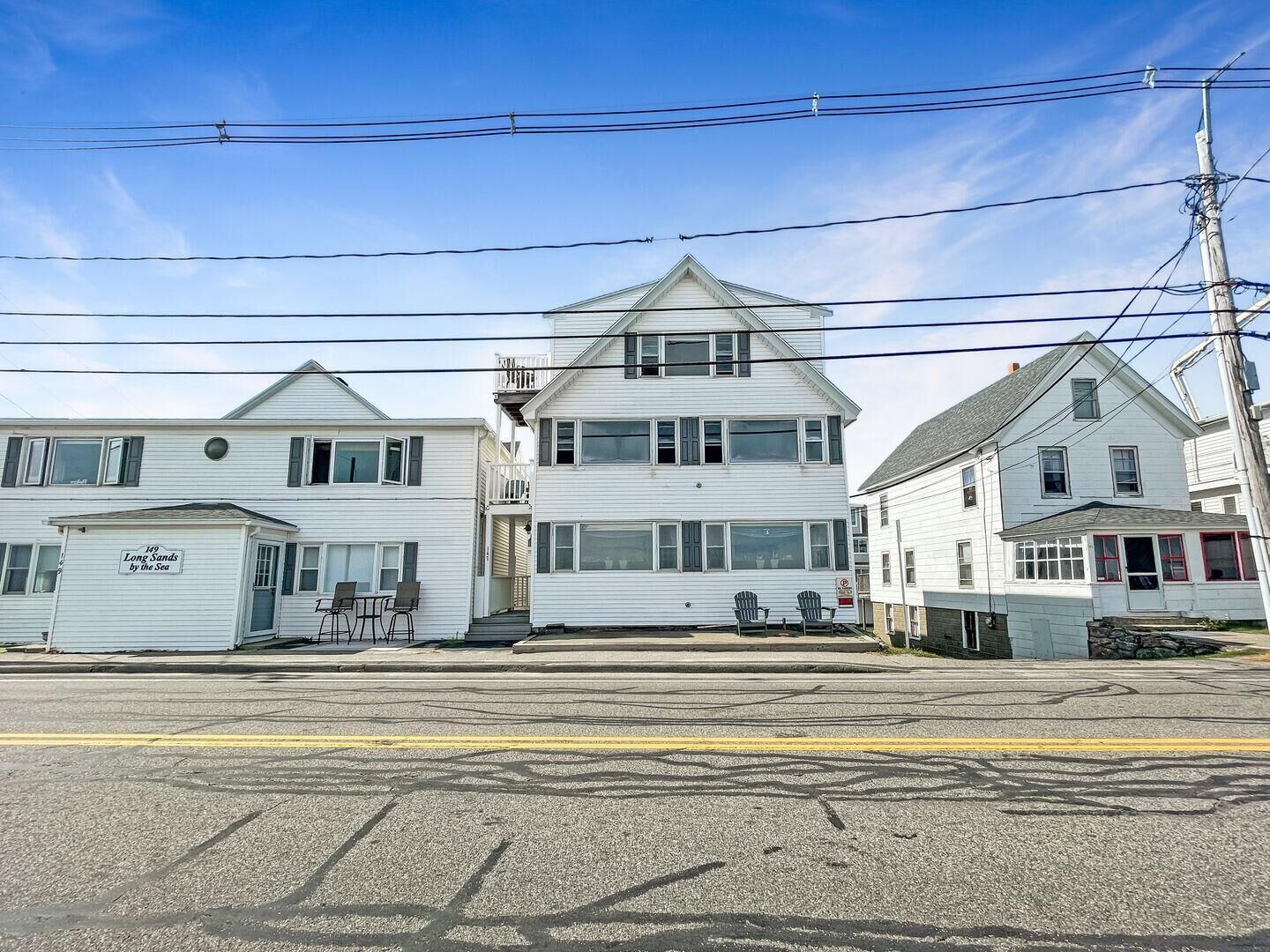 A row of white, two-story houses with a garage on the left, a central house with a gabled roof, and a house with a red door on the right.