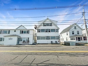 A row of white, two-story houses with a garage on the left, a central house with a gabled roof, and a house with a red door on the right. - Sweet Serenity (York Beach)
