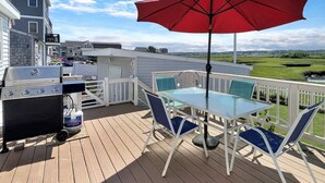 A deck with a grill, a table with chairs, and a red umbrella. - Sweet Dreams (Wells)