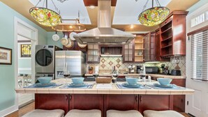 A kitchen with a central island, stainless steel appliances, and a stained glass light fixture.