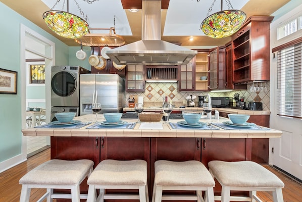 A kitchen with a central island, stainless steel appliances, and a stained glass light fixture.