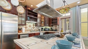 A kitchen with a stainless steel refrigerator, a gas stove, and a large island with blue bowls.