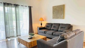 Ein modernes Wohnzimmer mit einem grauen Sofa, einem Holztisch und einer Lampe.