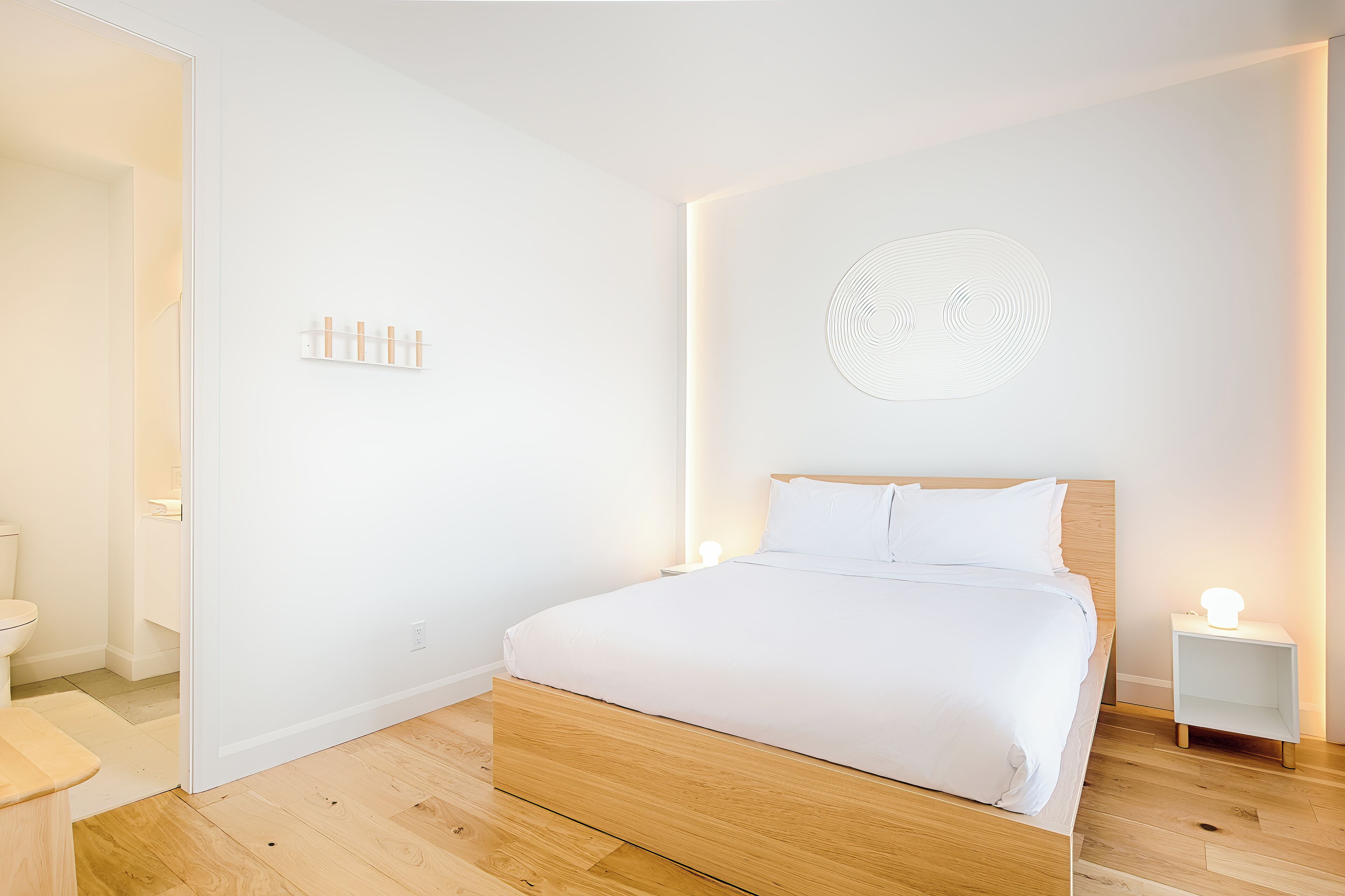Ein modernes Schlafzimmer mit einem Holzbett, weißen Wänden und minimalistischer Gestaltung.