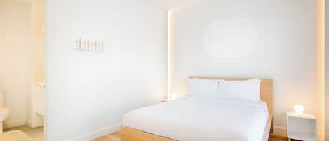 Ein modernes Schlafzimmer mit einem Holzbett, weißen Wänden und minimalistischer Gestaltung.