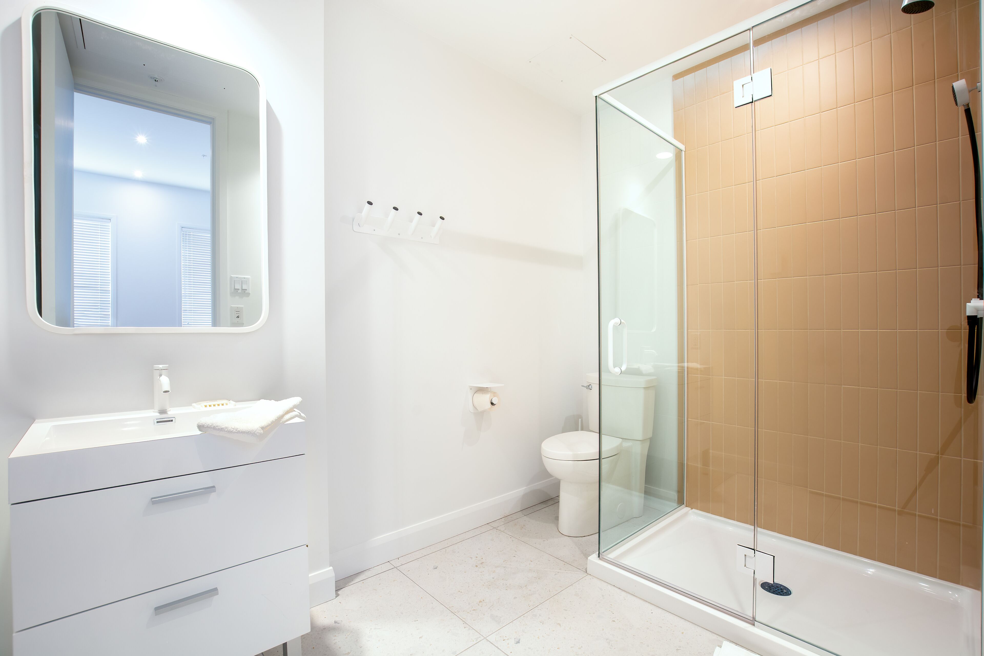 A modern bathroom with a glass-enclosed shower, a white sink with a mirror, and a toilet.
