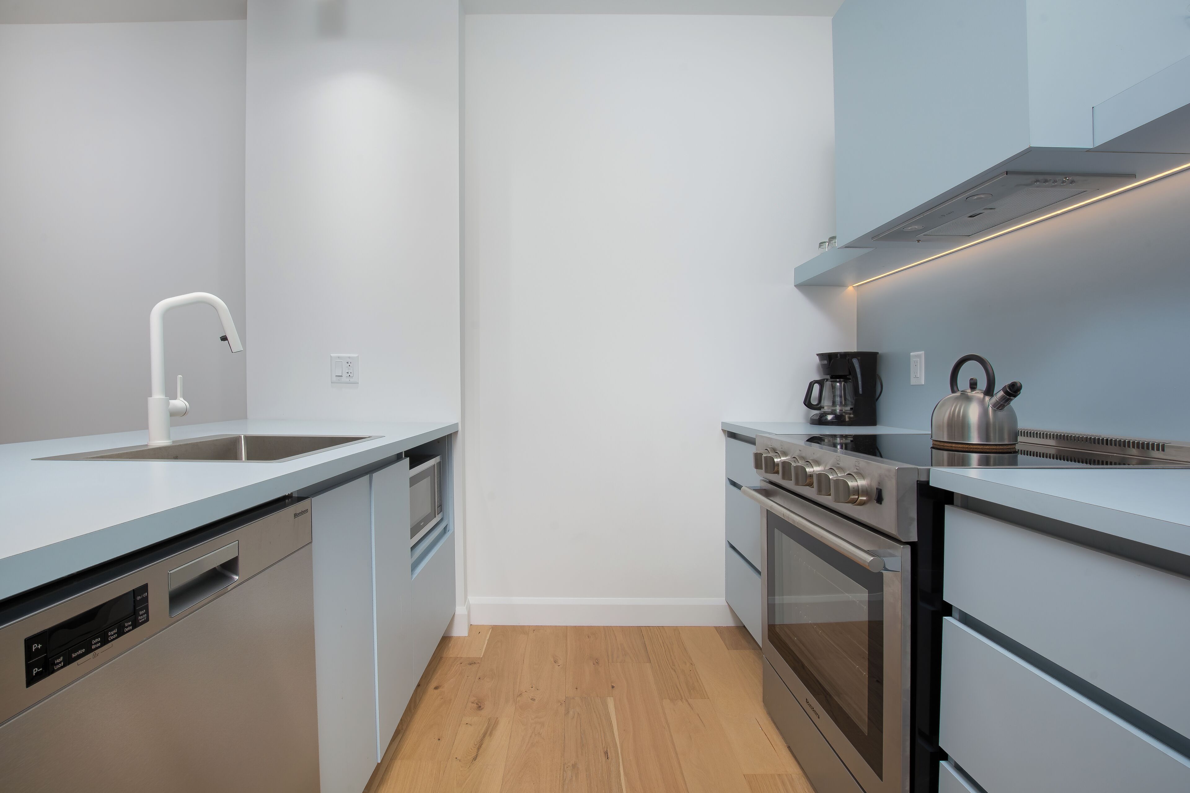 A modern kitchen with a dishwasher, oven, and coffee maker.