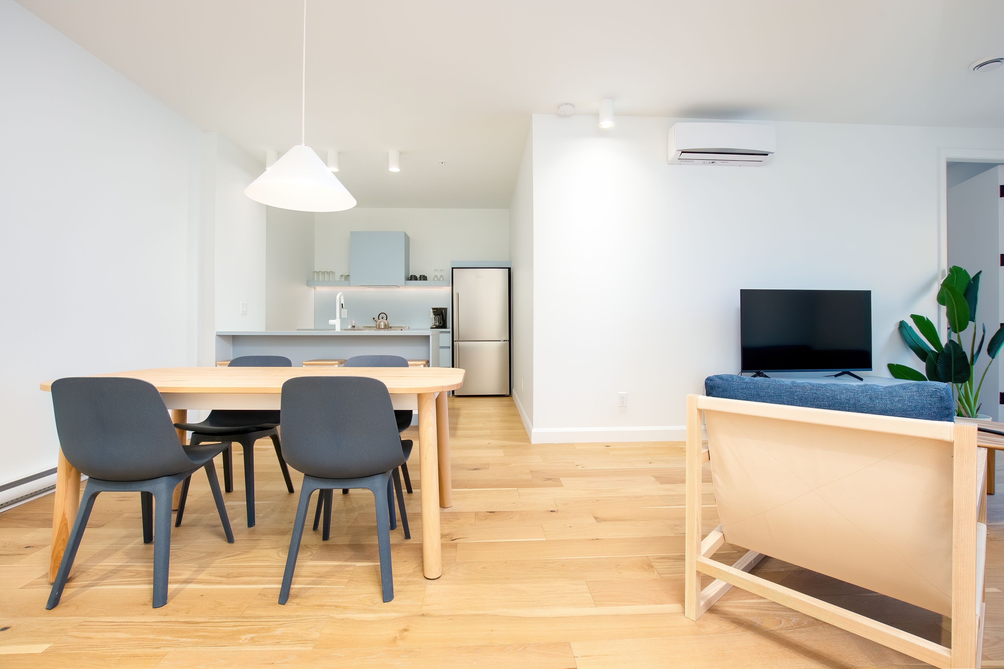 A modern living space with a dining area, kitchen, and a TV area.
