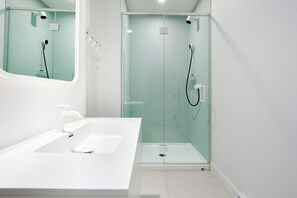 Un bany modern amb un rentapans blanc, una cabina de dutxa de vidre i un mirall sobre el rentapans.