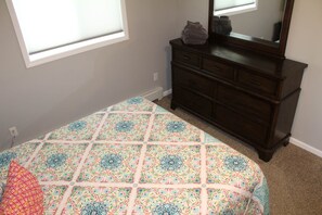 A bedroom with a bed, a dresser, and a window.