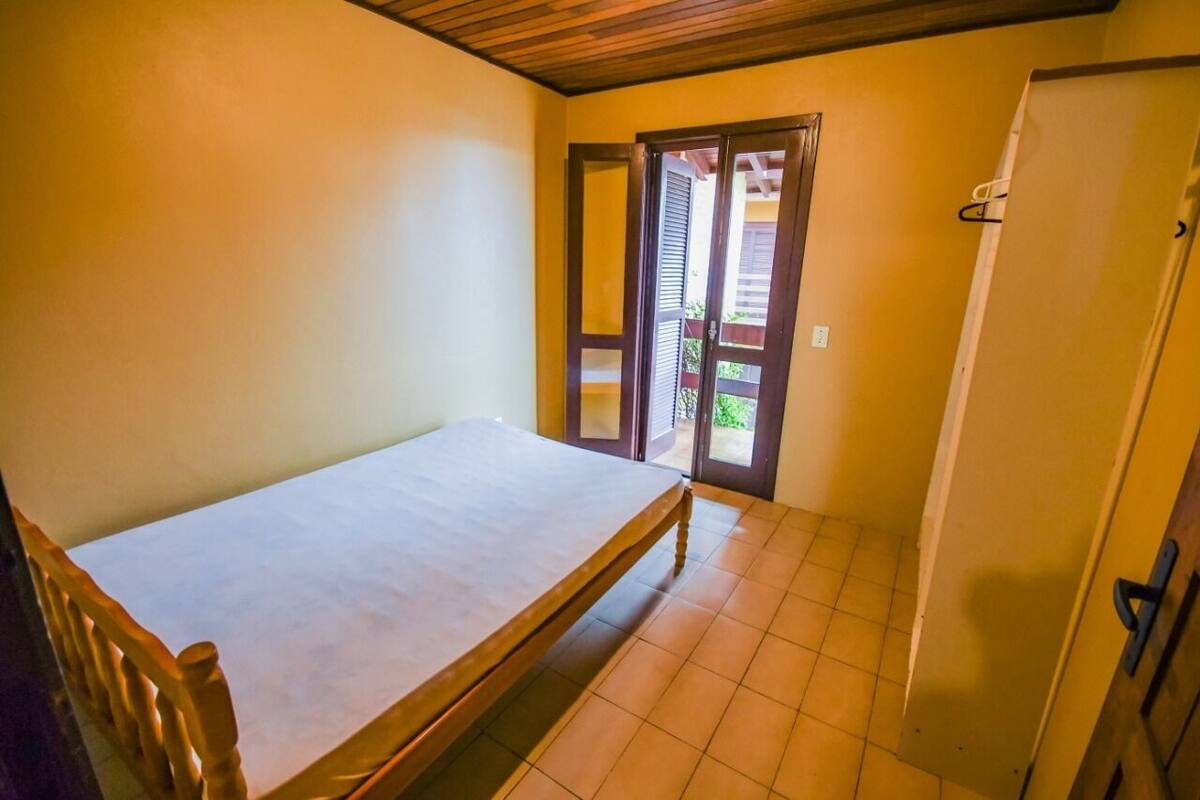 Ein Zimmer mit einem Bett, einer Tür zu einem Außenbereich und einem gefliesten Boden.