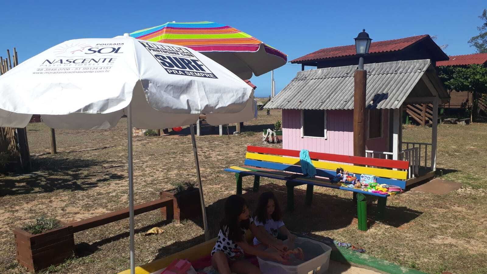 A beach scene with a colorful umbrella, a small wooden hut, and a bench with toys.