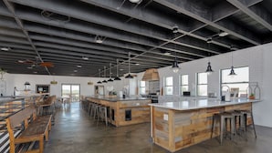 A spacious kitchen with a long counter, bar stools, and a high ceiling with exposed beams.