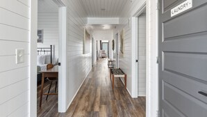 A hallway with white walls, a wooden floor, a dining area with a table and chairs, and a door labeled 'Laundry.'