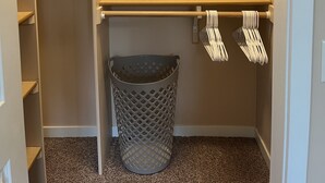 Vaatehuone, jossa on avohyllyjä, vaatetanko ja roskakori.