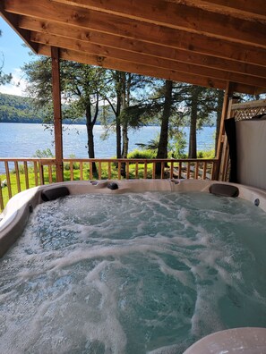 A hot tub with a wooden deck and a view of a lake. -  Romantic Cabin Getaway with Hot Tub (Rivière-Rouge)