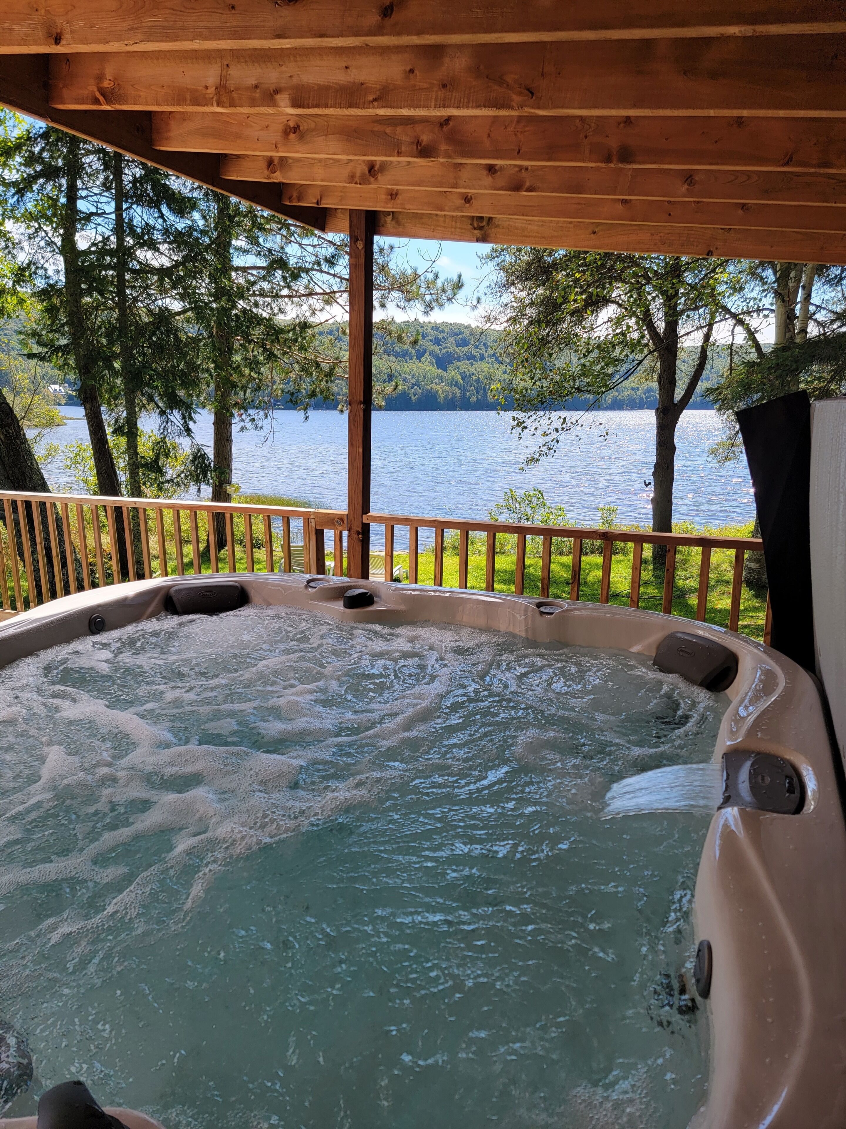 Ein Whirlpool mit einer Holzterrasse und Blick auf einen See.