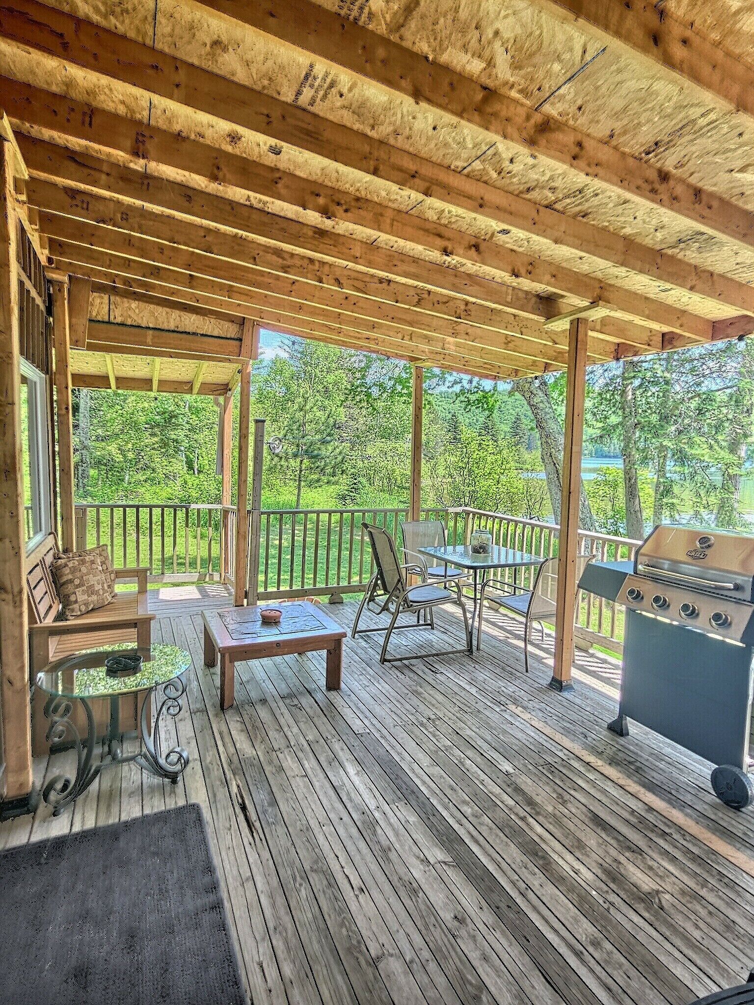 Une terrasse extérieure dotée d’une pergola en bois, d’un barbecue, d’une table en verre et d’un banc.