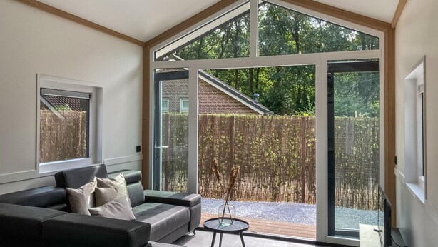 A modern living room with a large sliding glass door leading to a patio area.