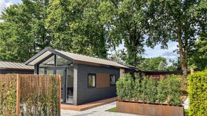 A modern house with a dark facade, large windows, and a sloped roof.