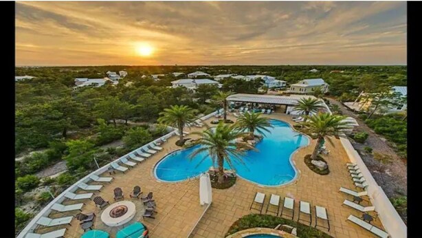 Ein Resort mit großem Pool, Liegestühlen und Blick auf die umliegende Landschaft bei Sonnenuntergang.