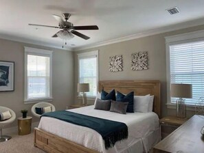 A bedroom with a bed, two bedside tables, a ceiling fan, and two wall-mounted lamps.