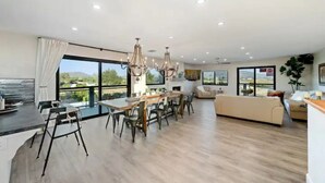 Amplia sala de estar con mesa de comedor, sofás y grandes ventanales que ofrecen vistas al exterior.