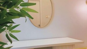 A room with a white wall, a round mirror, and a white chair with a yellow cushion. - Ice Apartel Lekki phase 1 (Lagos)