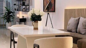 A modern dining area with a white table, two chairs, a vase with white flowers, and a tripod lamp. - Ice Apartel Lekki phase 1 (Lagos)
