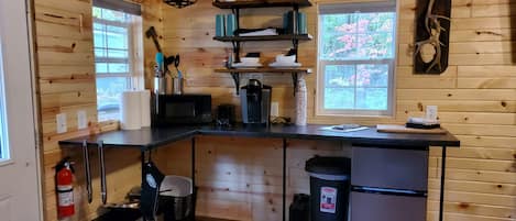 Una cocina compacta con paredes de madera, una isla central y una ventana con vistas a la vegetación.