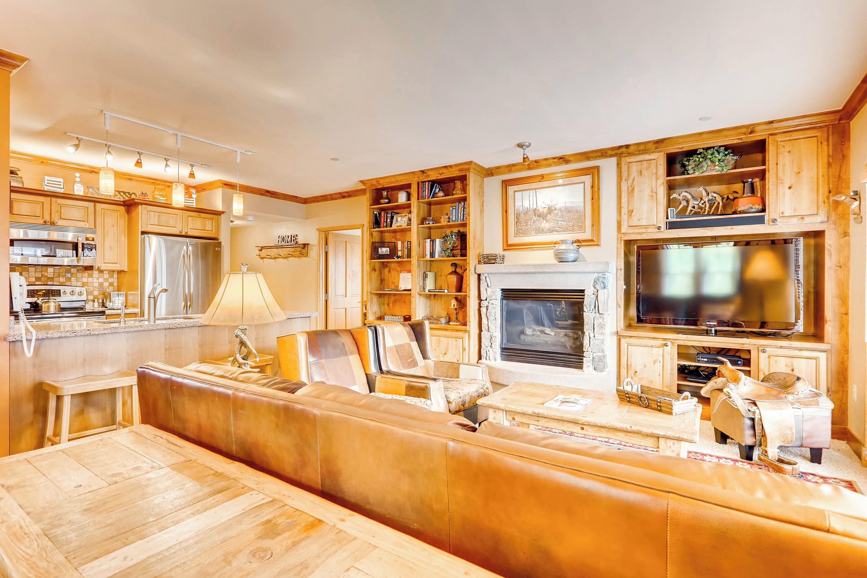 A spacious living area with a large wooden bench, a fireplace, and a television mounted above it.