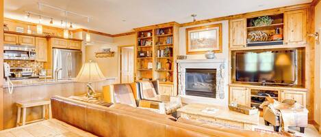 A spacious living area with a large wooden bench, a fireplace, and a television mounted above it.