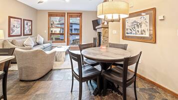A dining area with a round table and chairs, a sofa, and a fireplace.