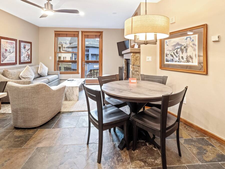 A dining area with a round table and chairs, a sofa, and a fireplace.