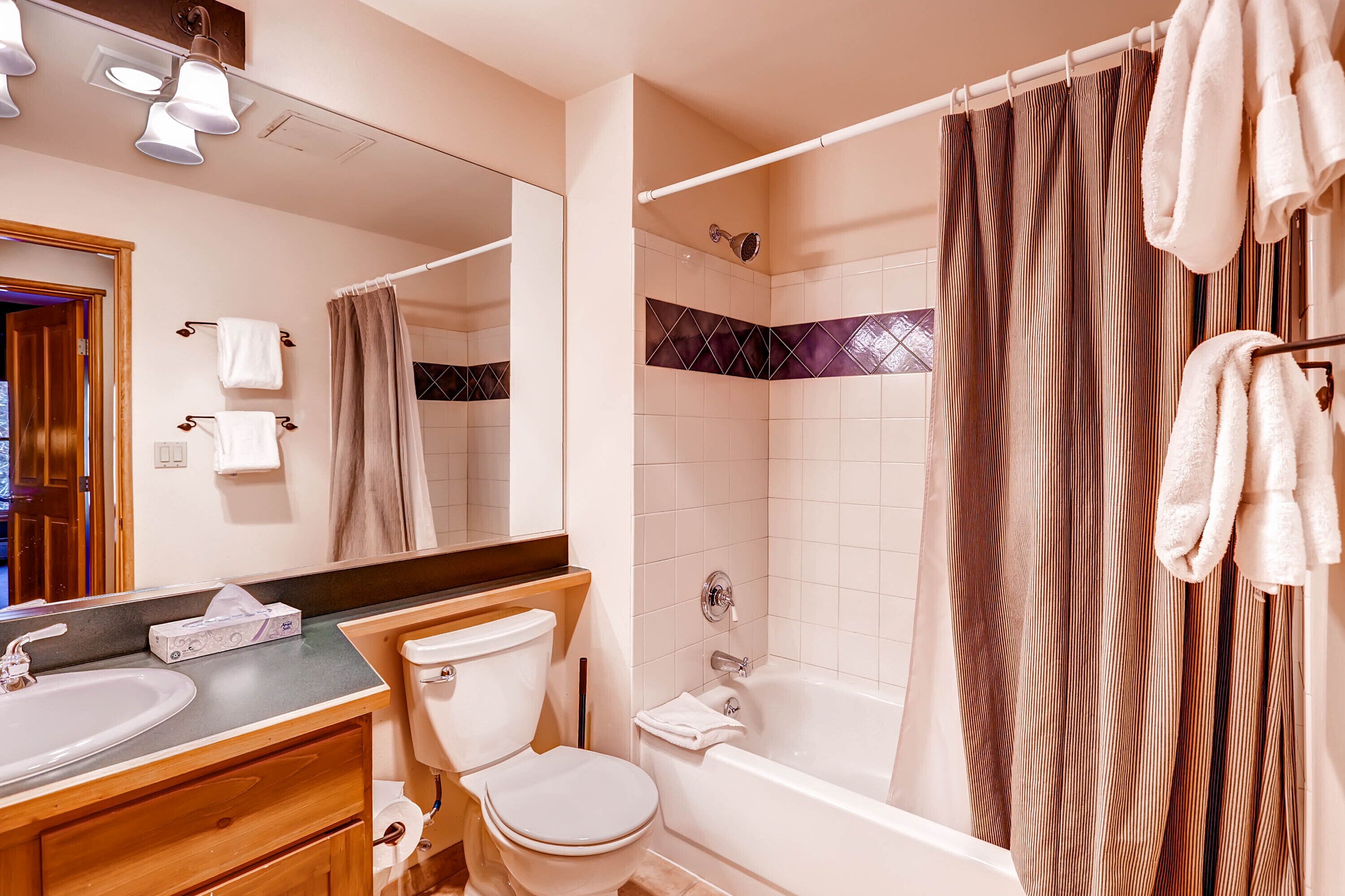 A bathroom with a sink, toilet, bathtub, and shower curtain.