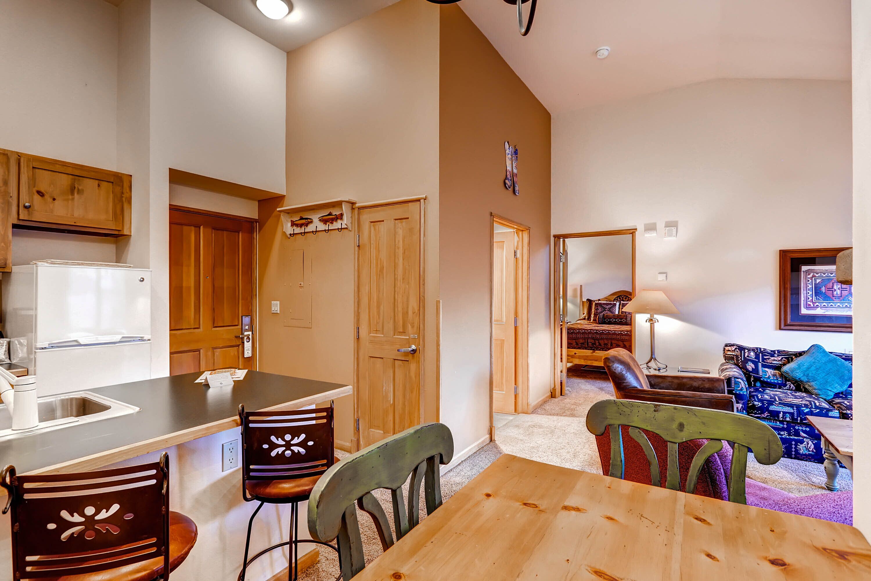 A compact kitchen with a dining area, wooden cabinets, and a refrigerator.