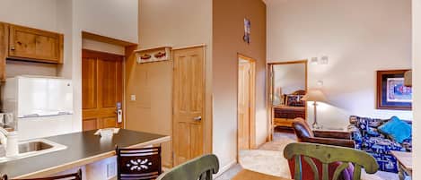 A compact kitchen with a dining area, wooden cabinets, and a refrigerator.