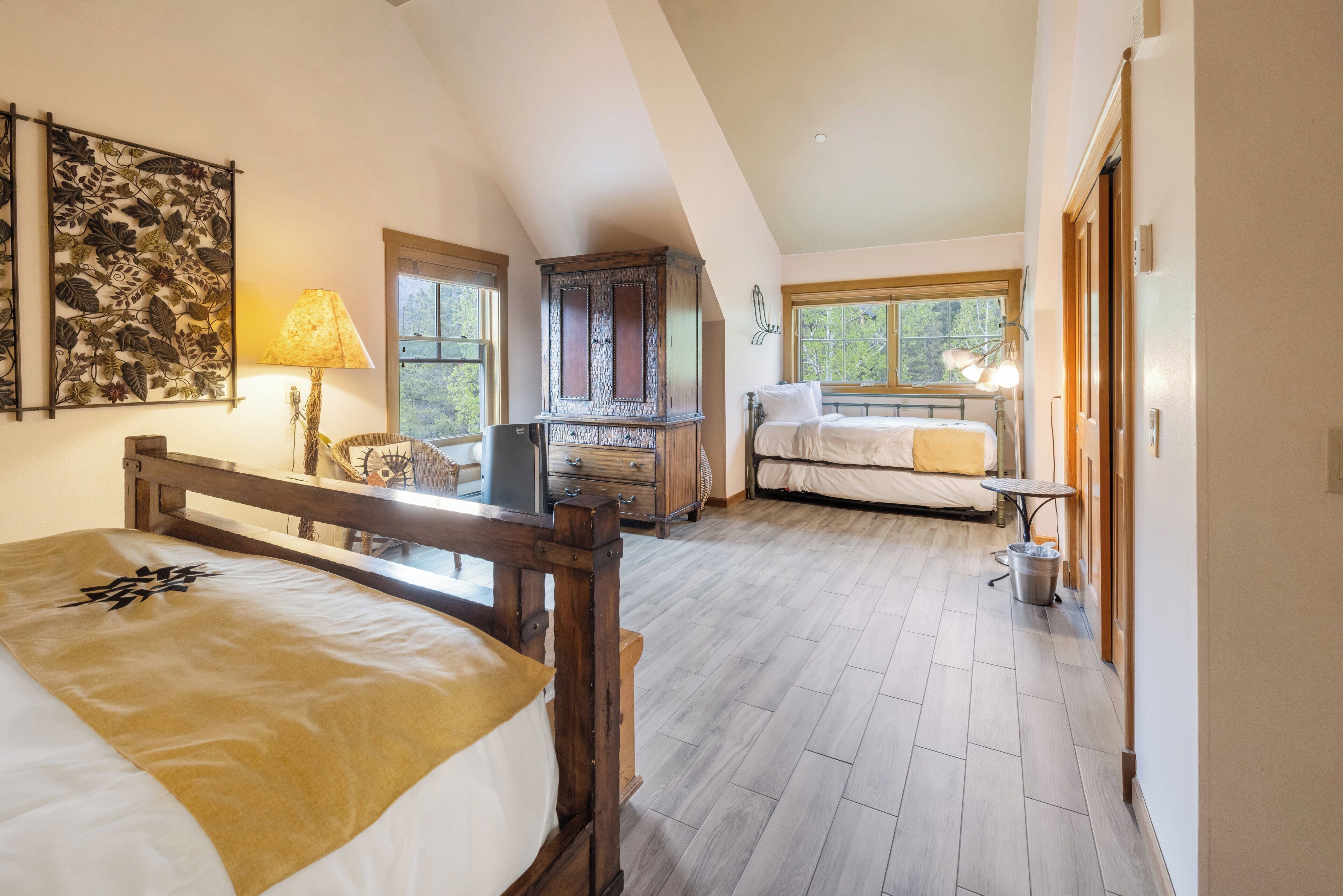 A bedroom with a wooden bed, a nightstand, a dresser, a window, and a lamp.
