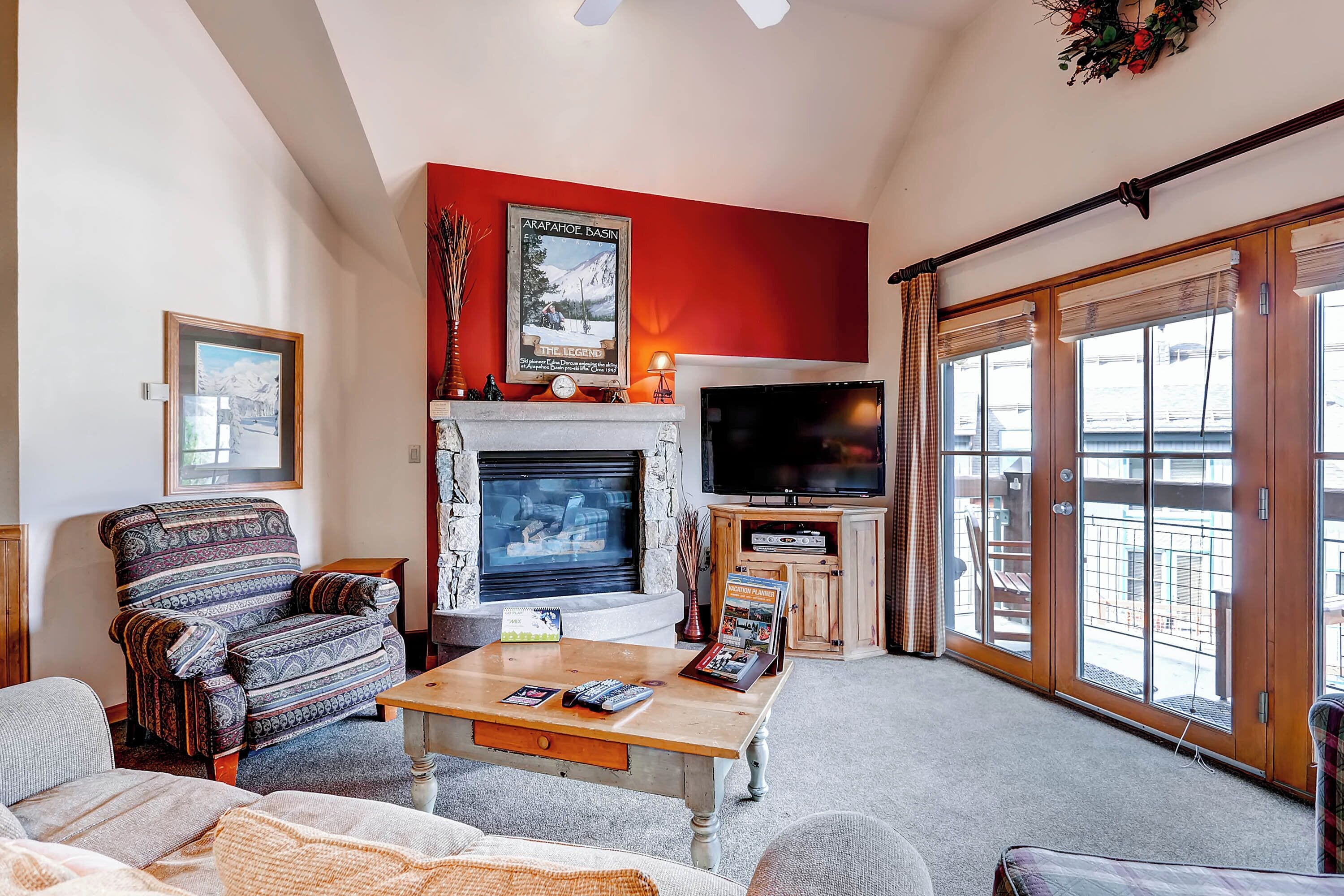 A living room with a fireplace, a television, and a large window.