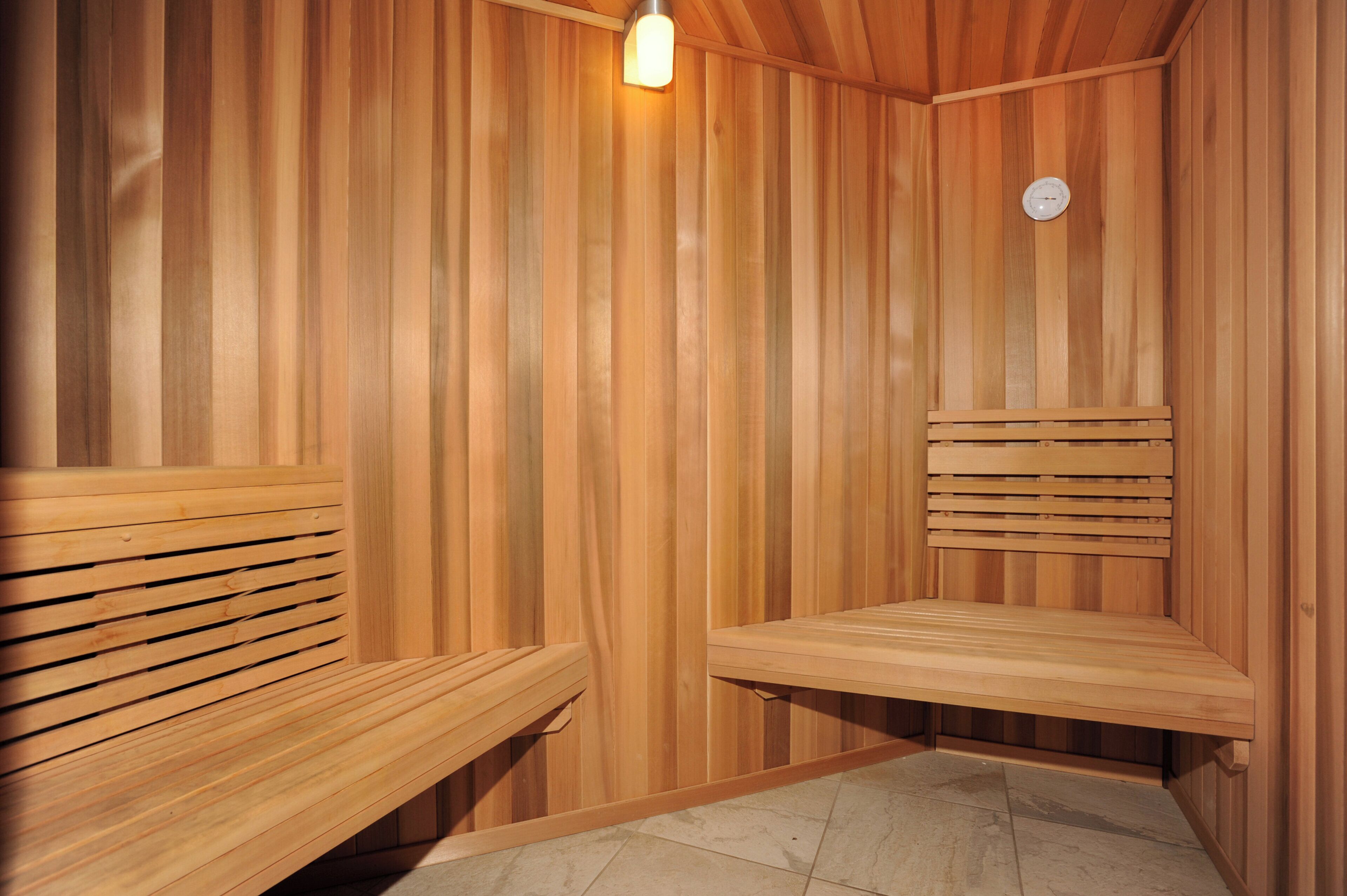 Un sauna en bois avec des bancs et un luminaire.