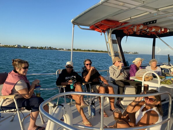A boat with passengers seated, a clear view of the water, and a distant shoreline. - Beach Villa 675 Steps to the pool and beach, 2 king bedrooms with private baths (Treasure Cay)