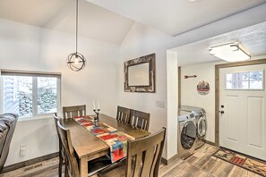 Un coin repas avec une table en bois, des chaises, une courtepointe et un luminaire suspendu.