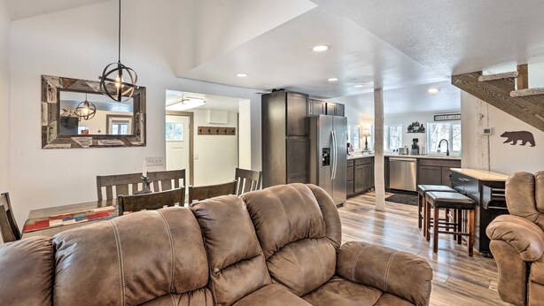 A spacious living room with a brown leather sofa, a dining area with a wooden table and chairs, a kitchen with stainless steel appliances, and a staircase leading to another level. - Cozy two bedroom cabin 10 min from Red Rocks 25 min from Denver  (Morrison)