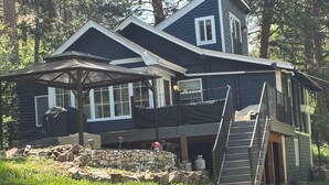 A two-story house with a covered patio, stone foundation, and a wooden staircase leading to an upper level. - Cozy two bedroom cabin 10 min from Red Rocks 25 min from Denver  (Morrison)