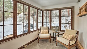A corner room with large windows, a fireplace, and two chairs with cushions. - Cozy two bedroom cabin 10 min from Red Rocks 25 min from Denver  (Morrison)